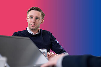 Klinikleiter Marius Trabert auf buntem Hintergrund